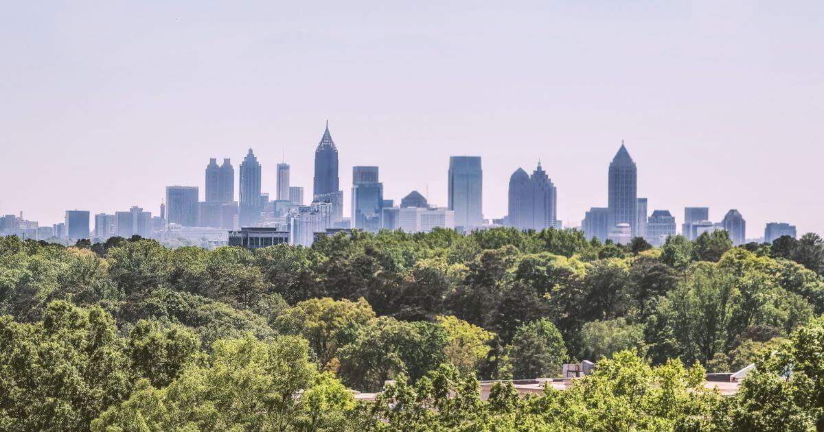 Photo of the Atlanta Skyline with skyscrapers in the background and trees in the foreground.