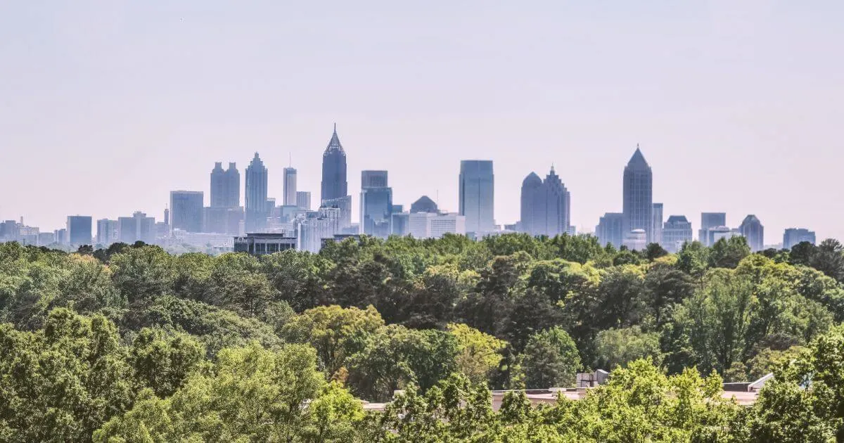 Photo of the Atlanta Skyline with skyscrapers in the background and trees in the foreground.