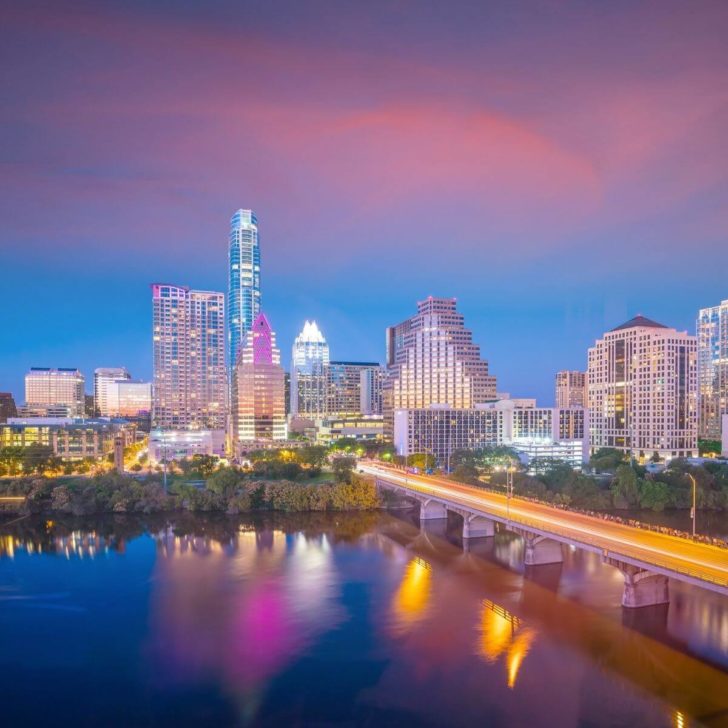 Photo of the Austin skyline at dusk with the Colorado River in the foreground.