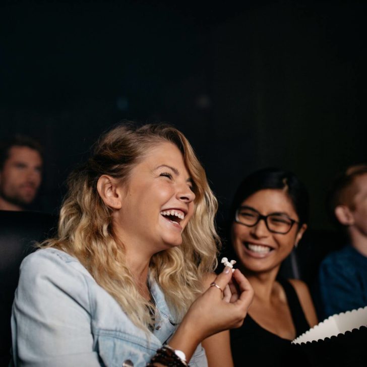 Photo of women sitting in an audience of a show, laughing.