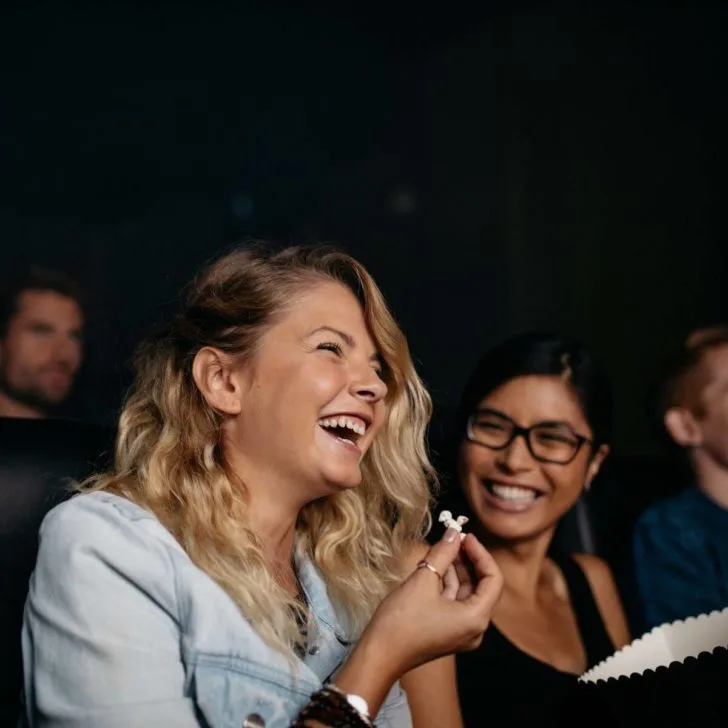 Photo of women sitting in an audience of a show, laughing.