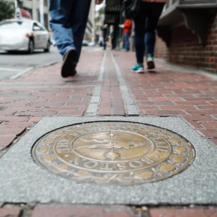 Photo of a Boston Freedom Trail marker settled in a brick sidewalk.