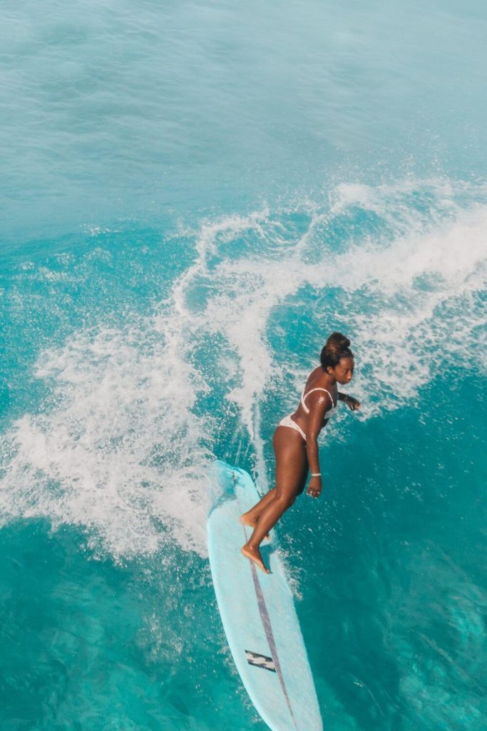 Photo of a woman in a bikini surfing a large wave in Hawaii.