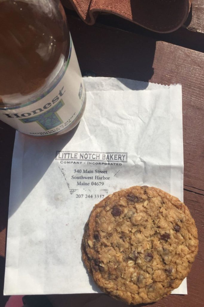 Flat lay photo of a bottle of iced tea, and an oatmeal cookie with a bakery bag with a stamp that says "Little Notch Bakery."