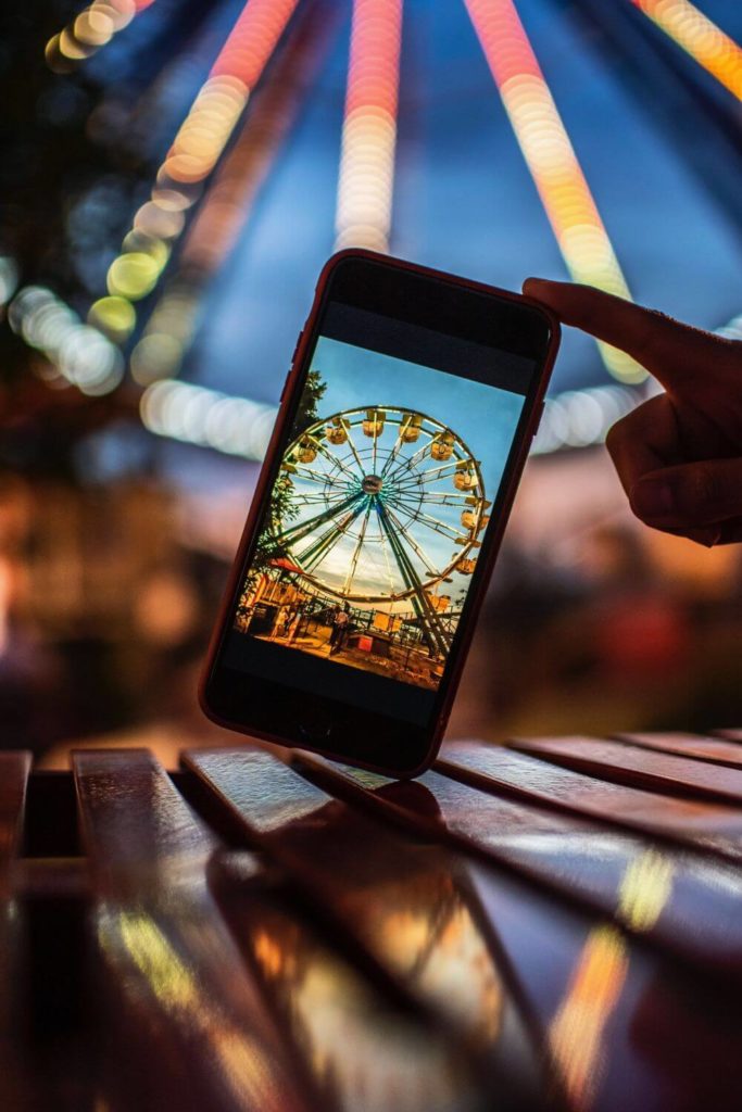 Photo of an iPhone taking a photo of a ferris wheel at dusk.