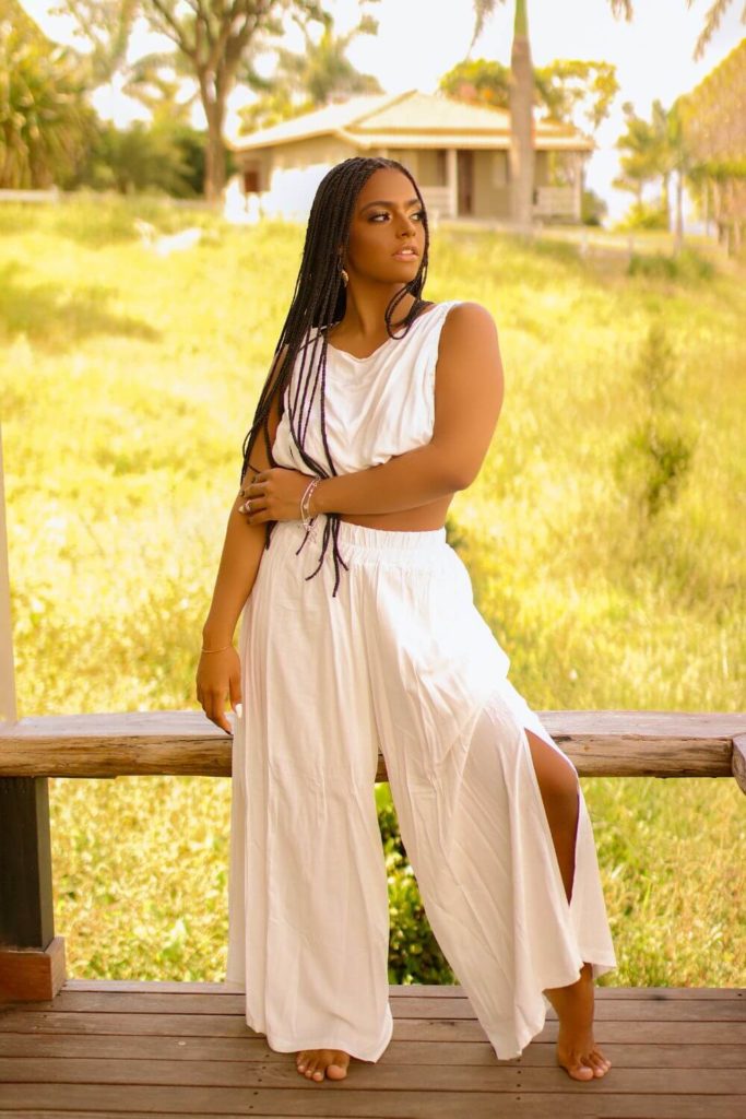 Photo of a woman wearing a breezy, white coordinated crop top and wide leg pants.