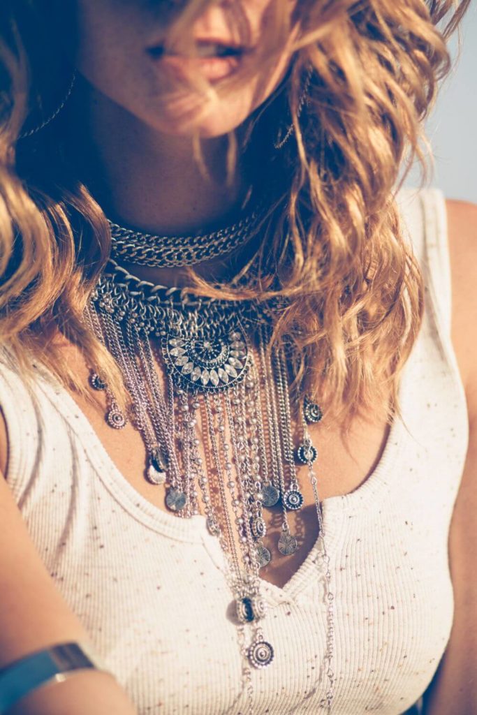 Closeup of a woman wearing a white ribbed tank top and a massive southwestern-inspired necklace.