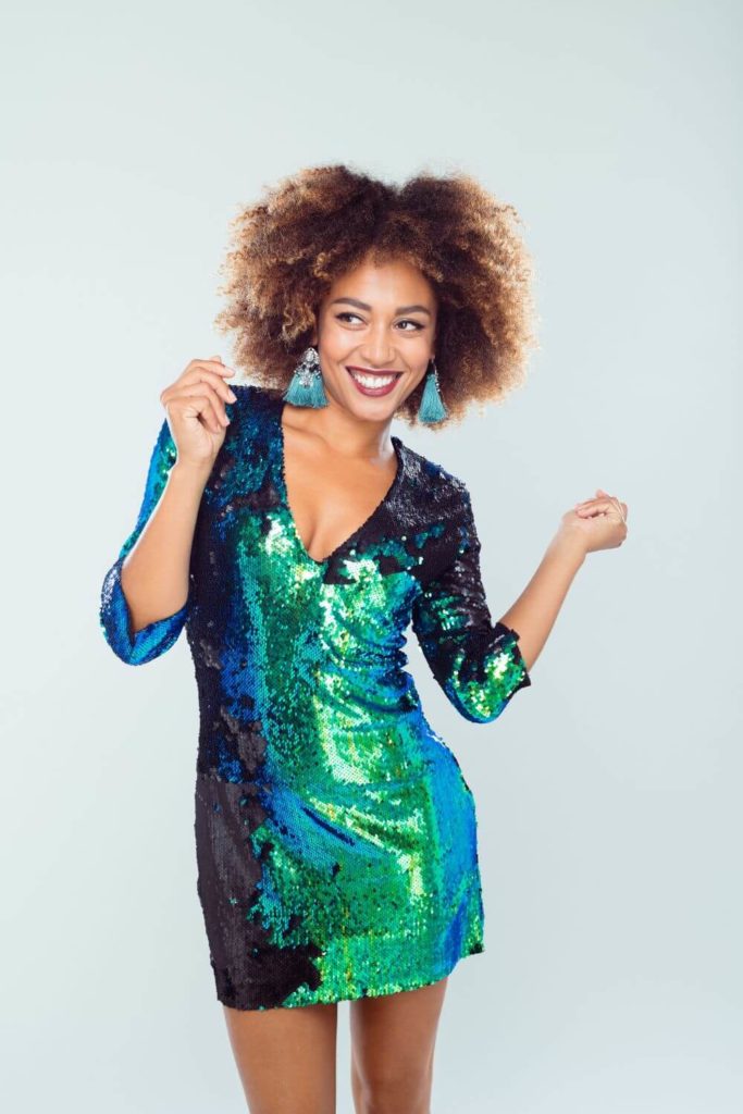 Photo of a black woman wearing a blue and green sequin dress.