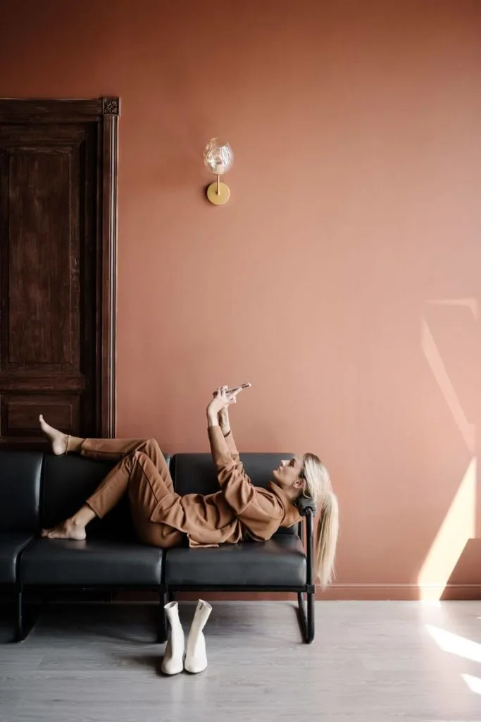 Photo of a woman laying on a sofa taking a selfie with a pair of white platform boots in front of the couch.