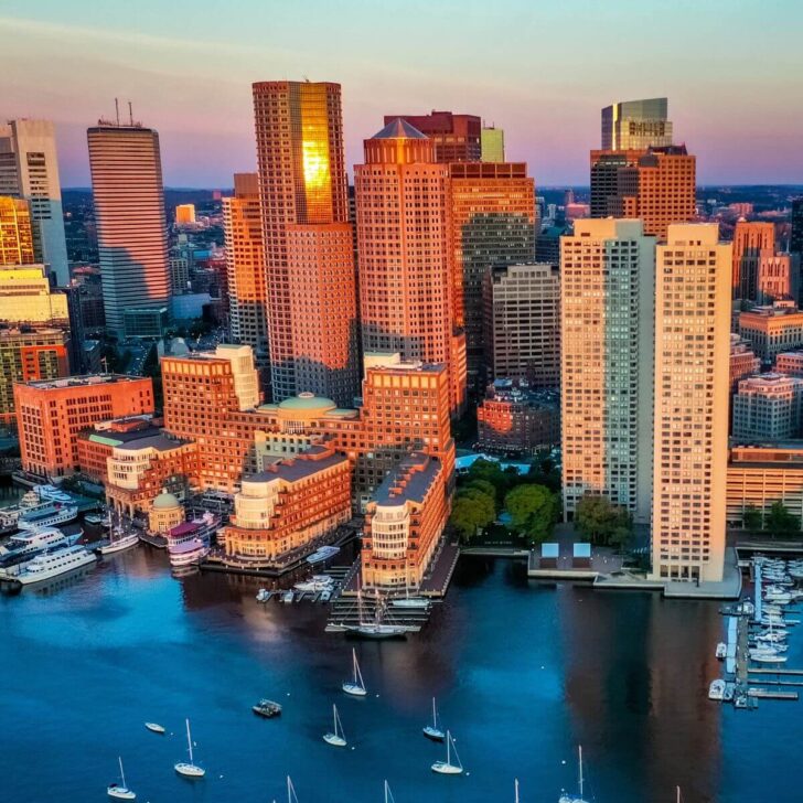 Photo of the Boston Harbor with the city skyline and sunset in the background.