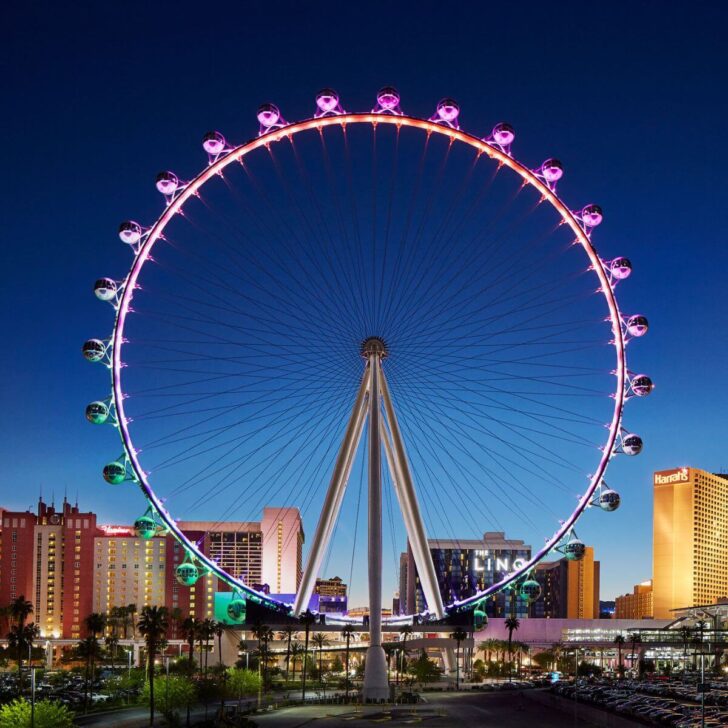 Photo of the High Roller in Vegas at night, lit up in violet and green.