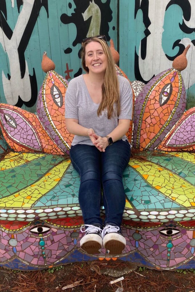 Photo of travel blogger Meg Frost sitting on a mosaic-encruisted couch in New Orleans, Louisiana, on a New Year getaway vacation.