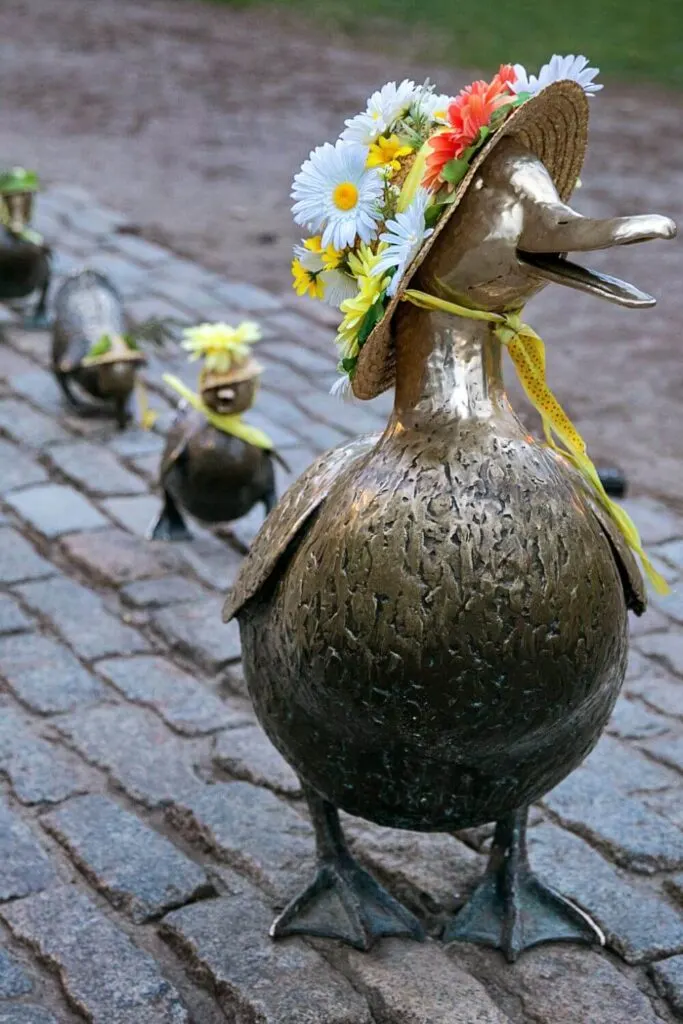 Photo of the Make Way for Ducklings statues in Boston Public Garden, with Spring themed hats on the statues.