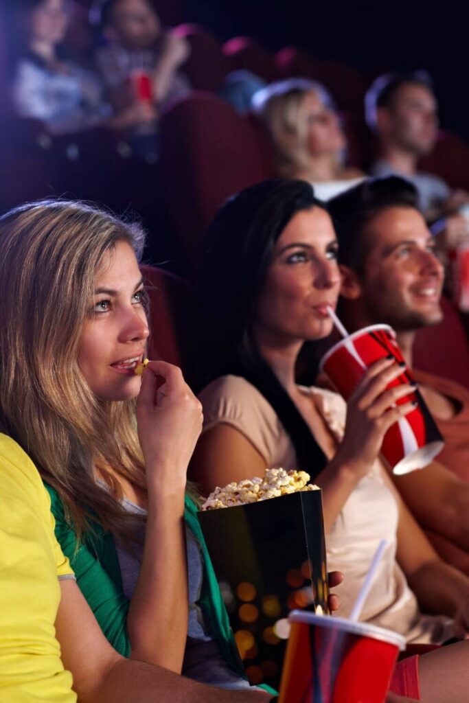 Photo of people watching a movie in a theater while eating snacks.