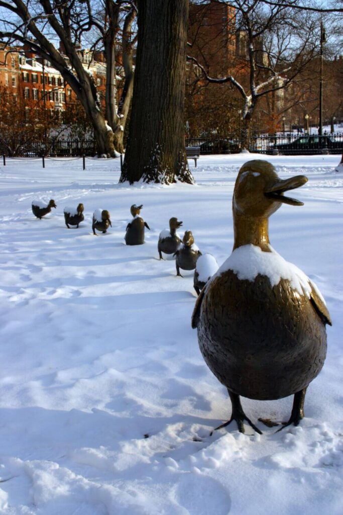 Photo of the Make Way for Duckling statues in the Boston Public Garden with a fresh layer of snow on them.