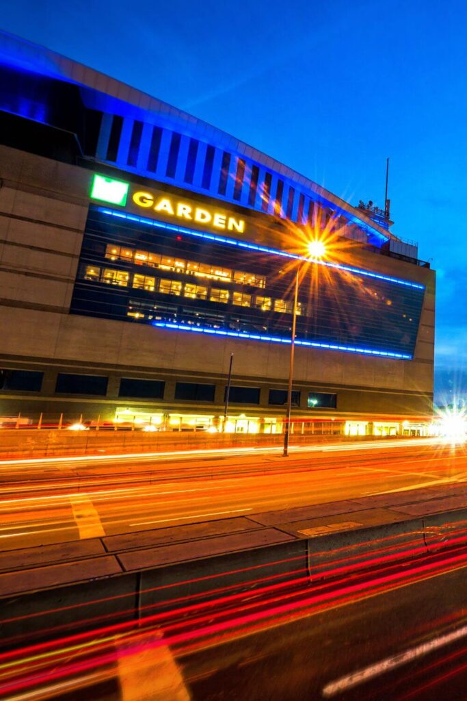 Photo of TD Garden at night with light trails from cars driving past.
